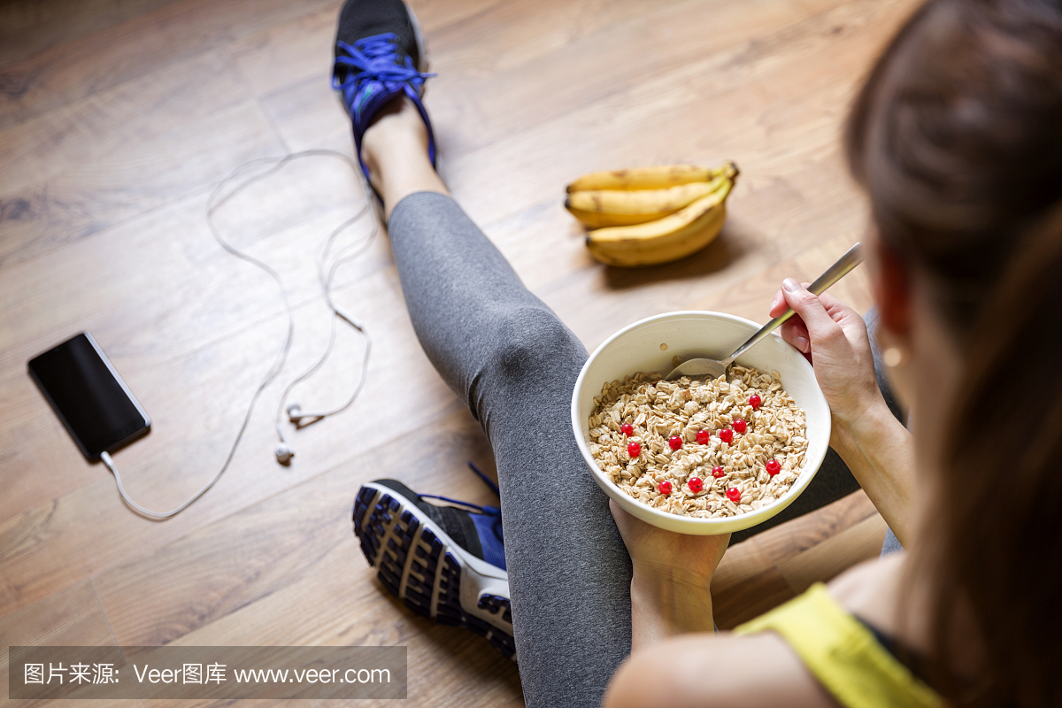 年轻女孩在锻炼后吃浆果燕麦粥。健身和健康的