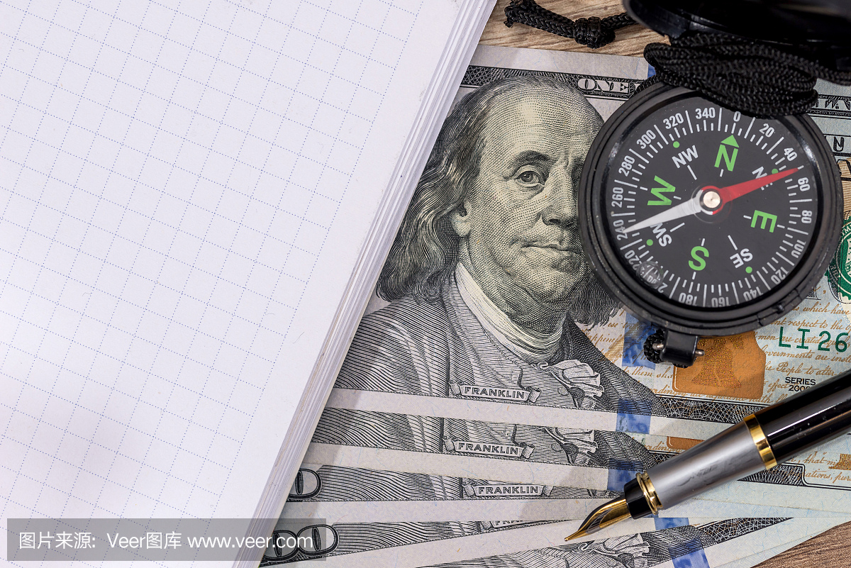 指南针在美国一百美元与笔记本。旅程概念。