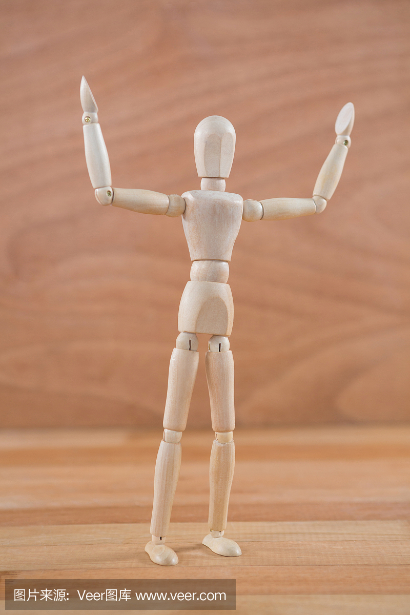 用手举起的木制小雕像站立