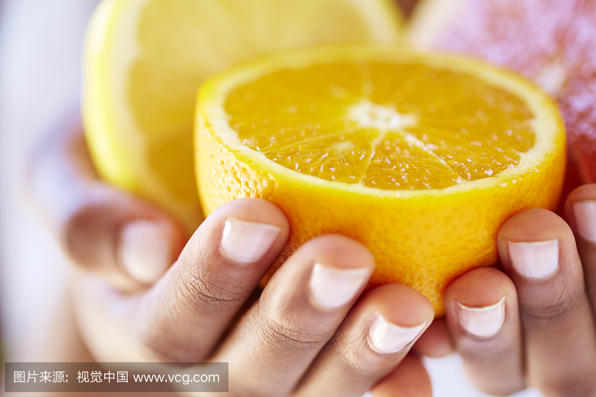 女子手拿着一半的橙子和葡萄柚