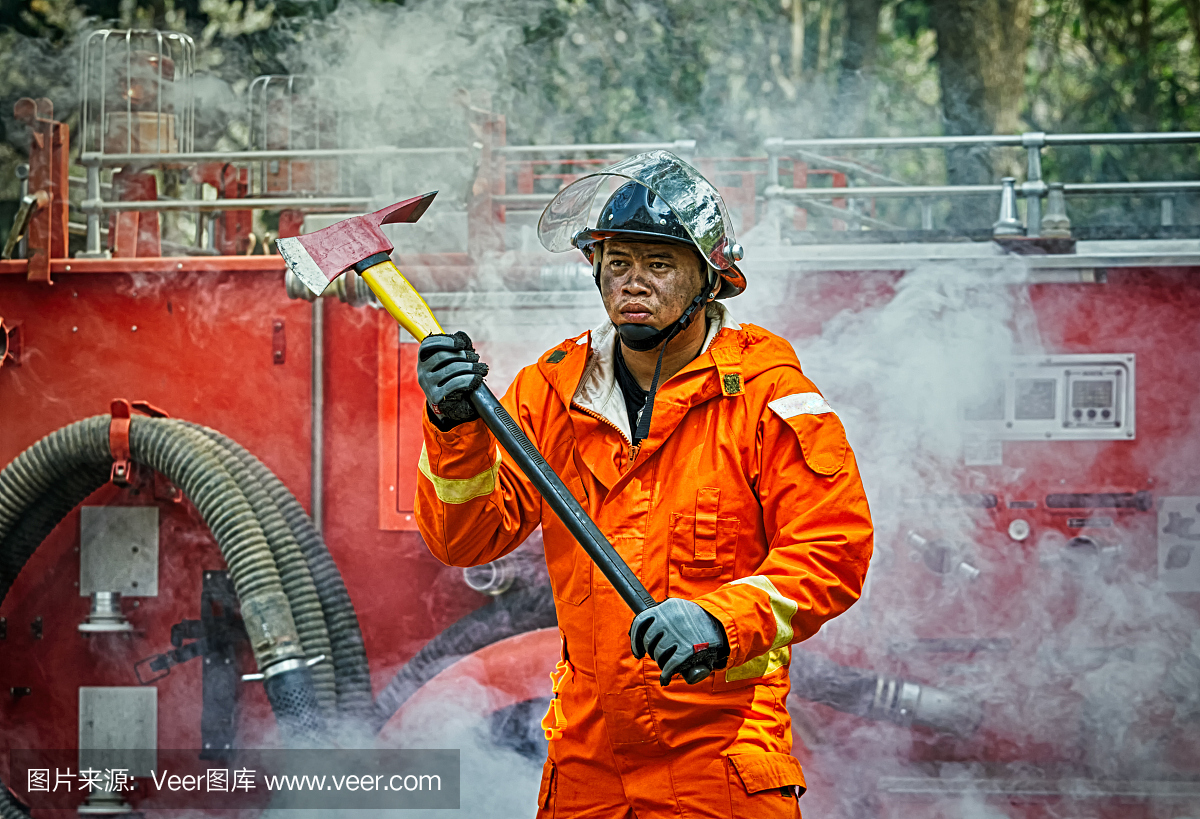 紧急消防训练,穿制服的消防员,带着消防斧的手
