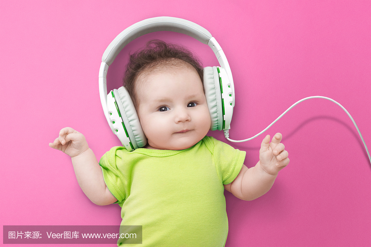 快乐的微笑新生婴儿在耳机听音乐