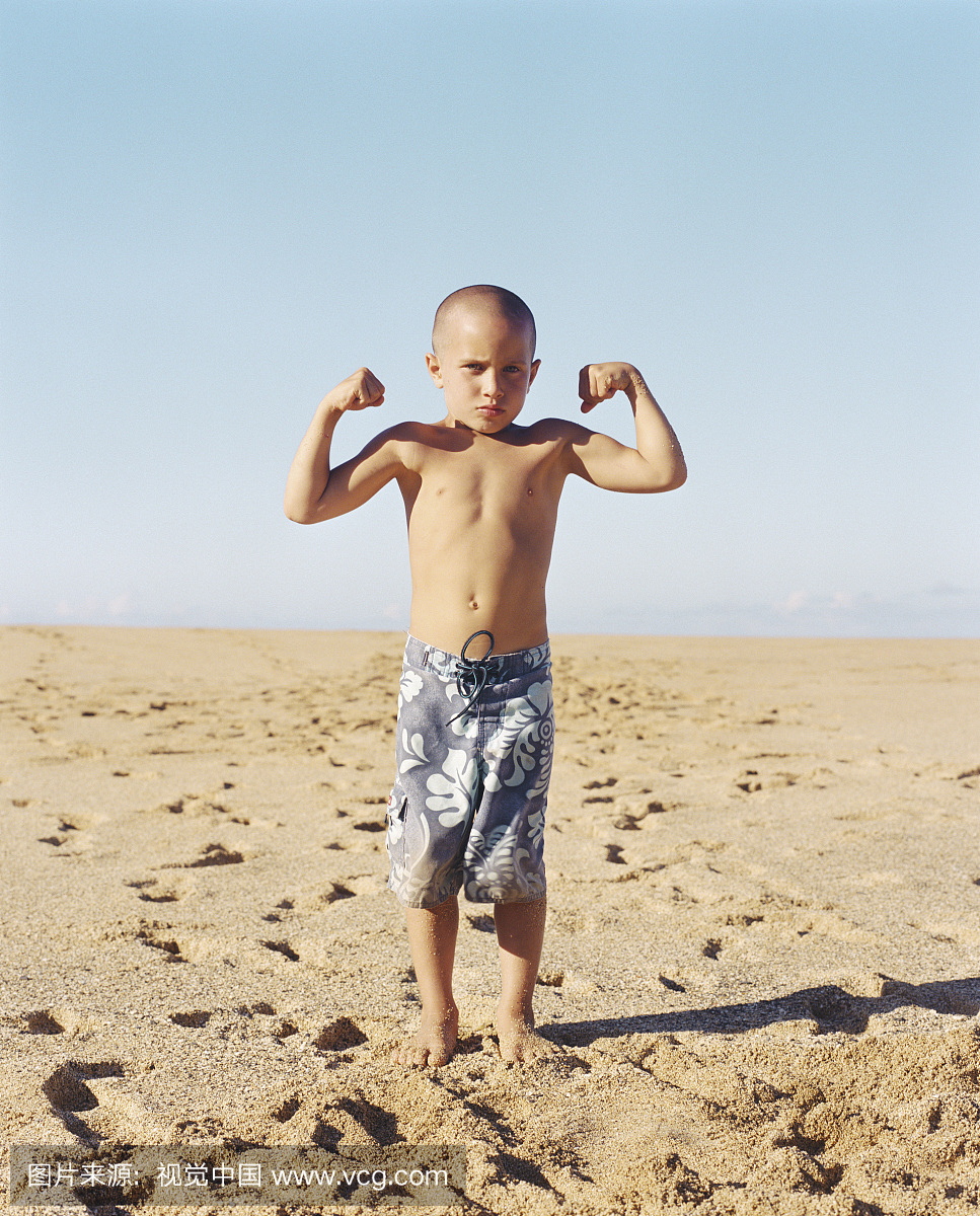 男孩站在海滩上弯曲肌肉