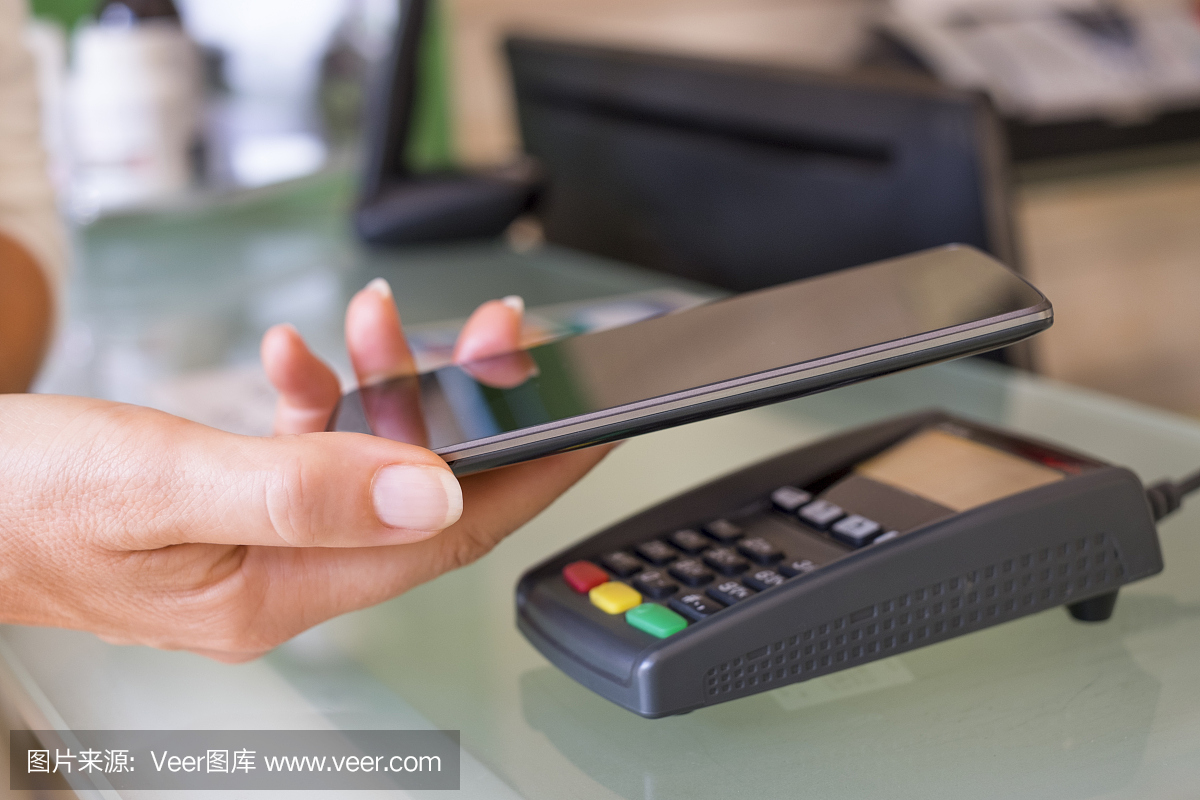 在美容师手机上用NFC技术支付的女人