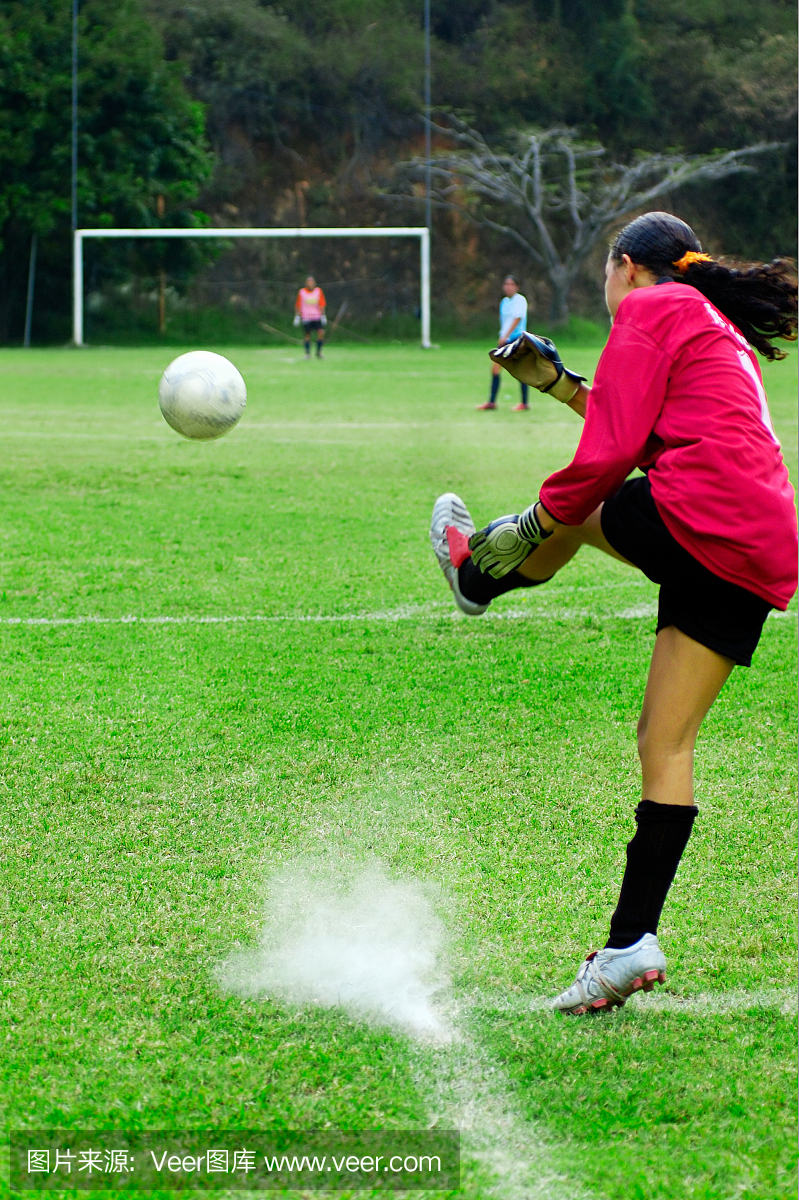 年轻女子打守门员,踢足球