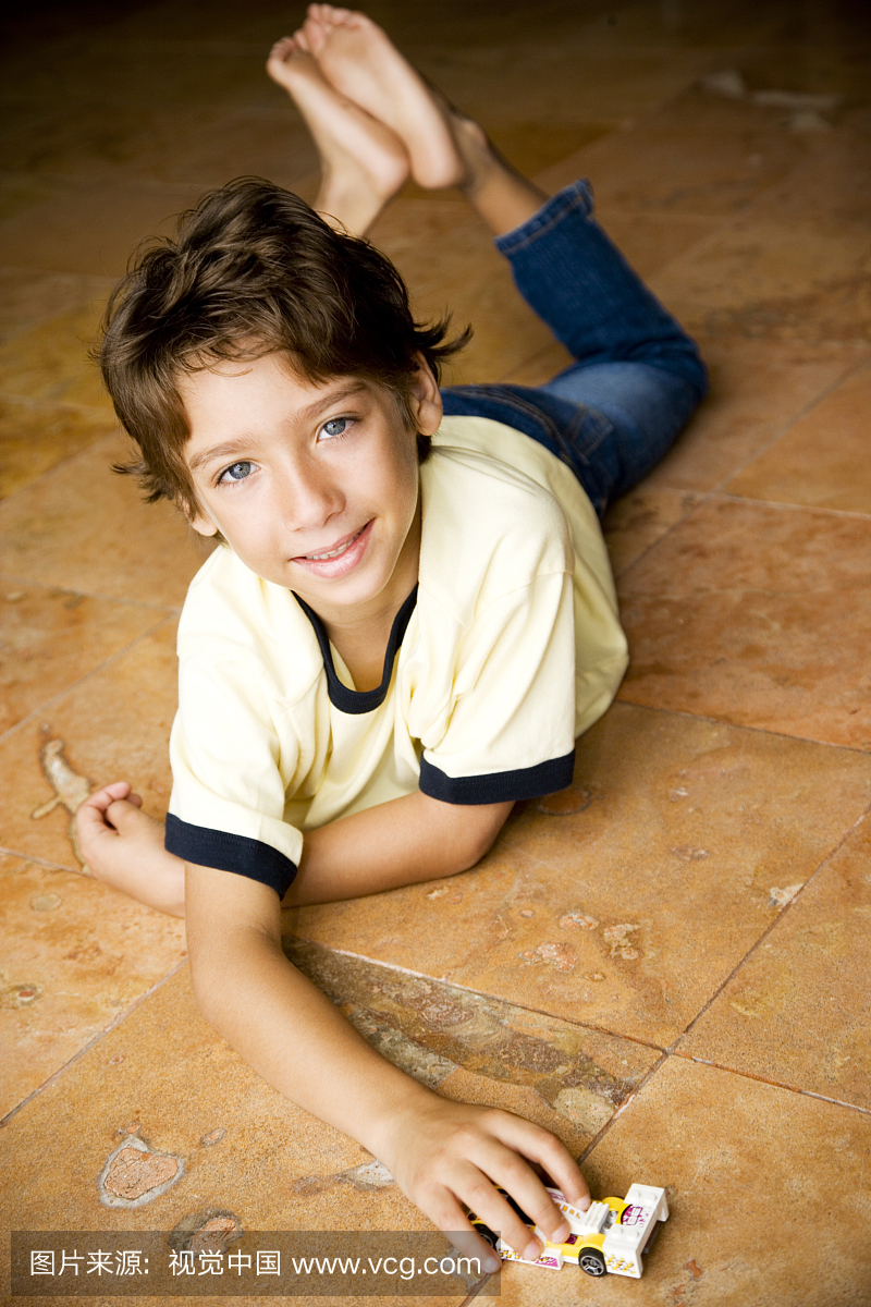 拉丁裔男孩玩玩具车在地板上