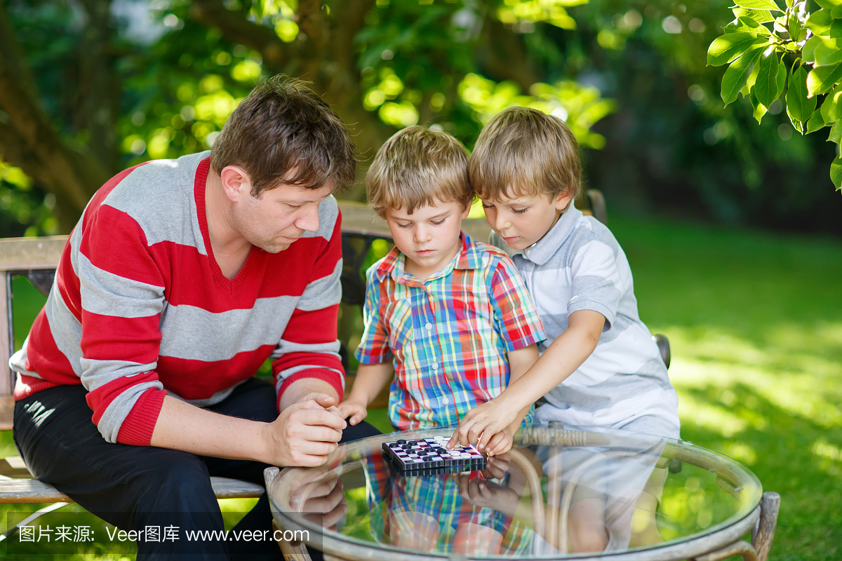 两个小孩男孩和父亲一起玩跳棋游戏