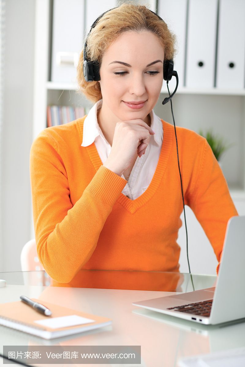 或通话操作员通过笔记本电脑通讯。橙色毛衣是