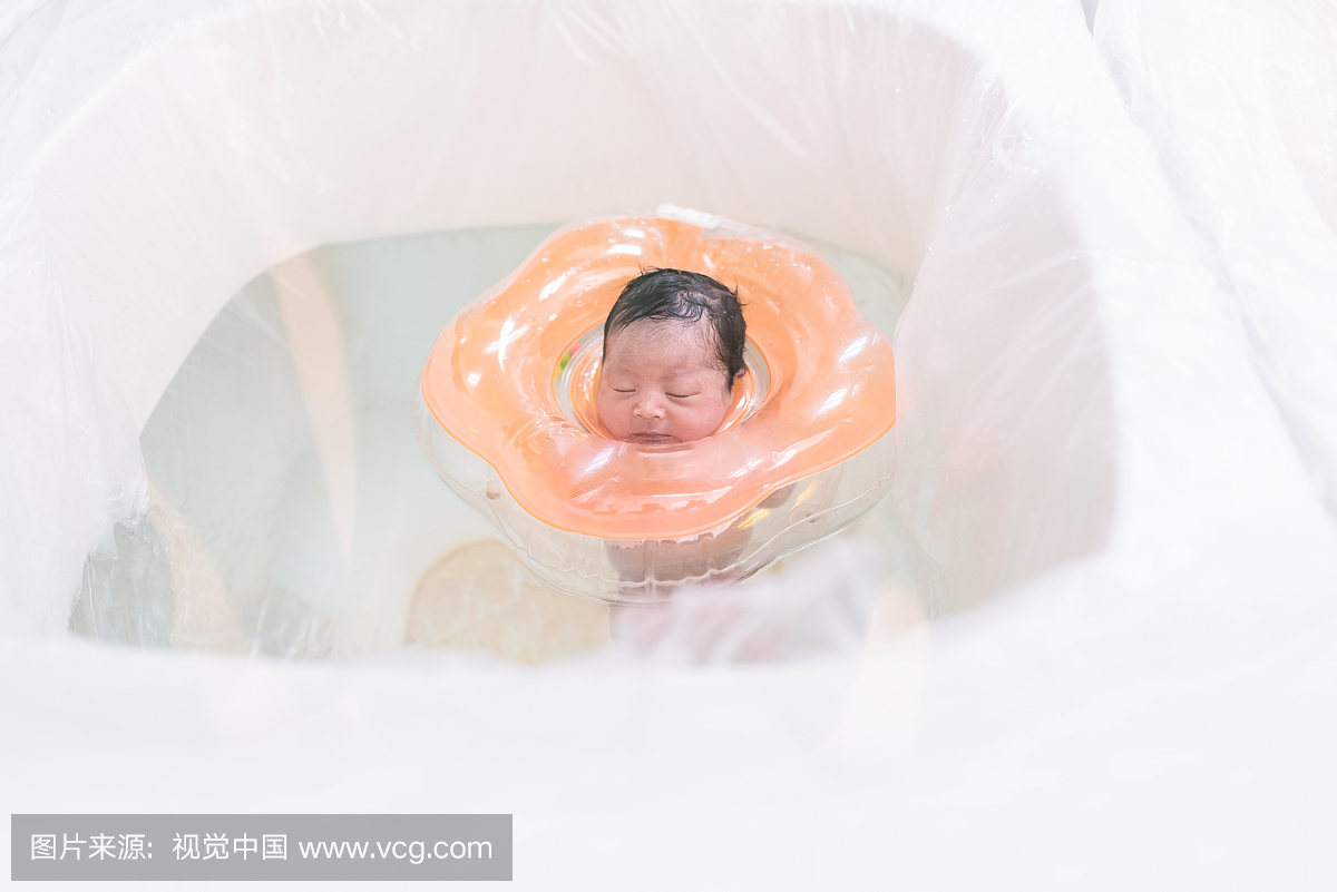 刚出生的婴儿女孩在游泳池里戴着可膨胀的圆环