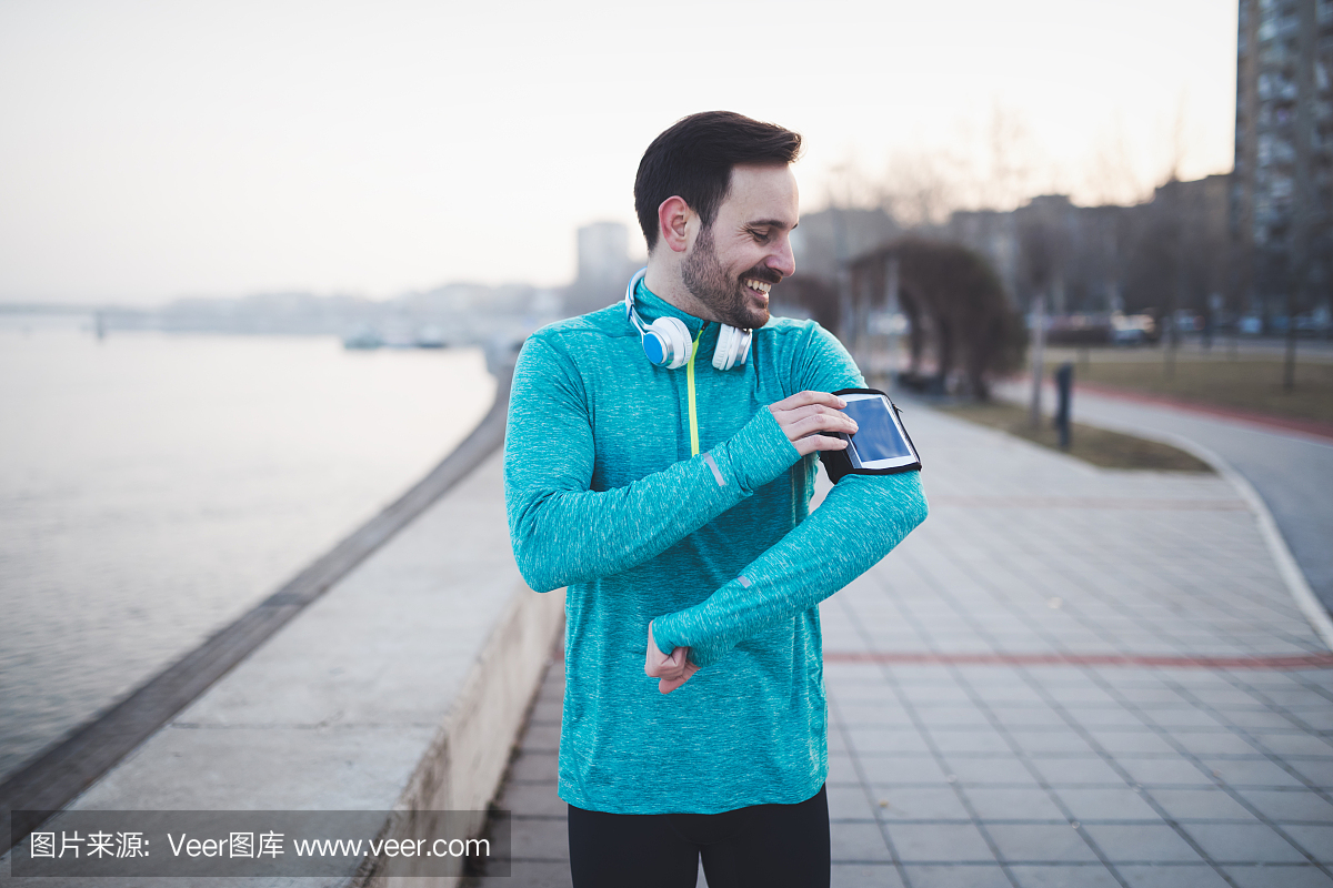 英俊健康的运动员在享受音乐时锻炼身体