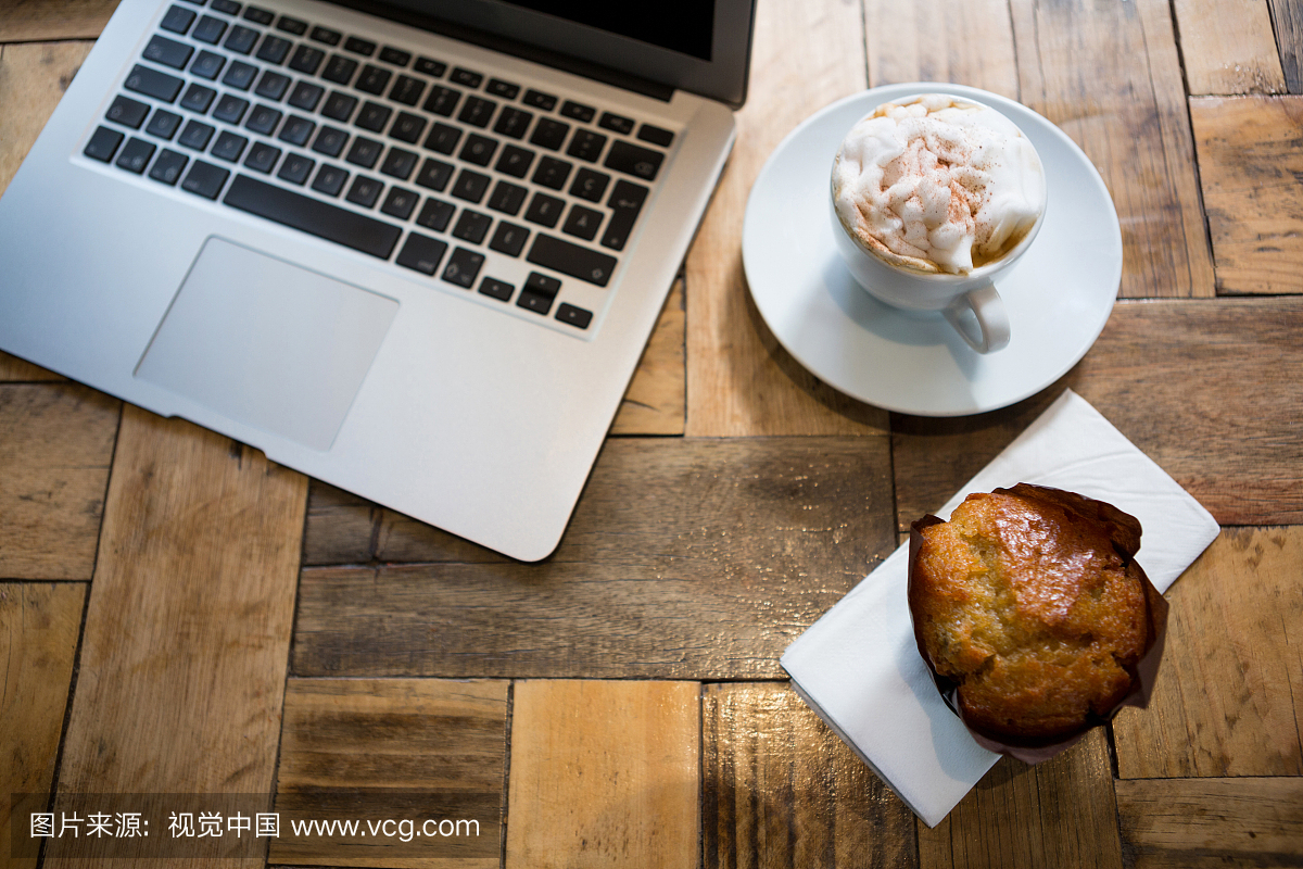 High angle view of laptop with coffee and muffin
