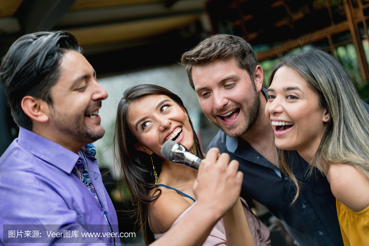 Happy group of people singing at a karaoke ba