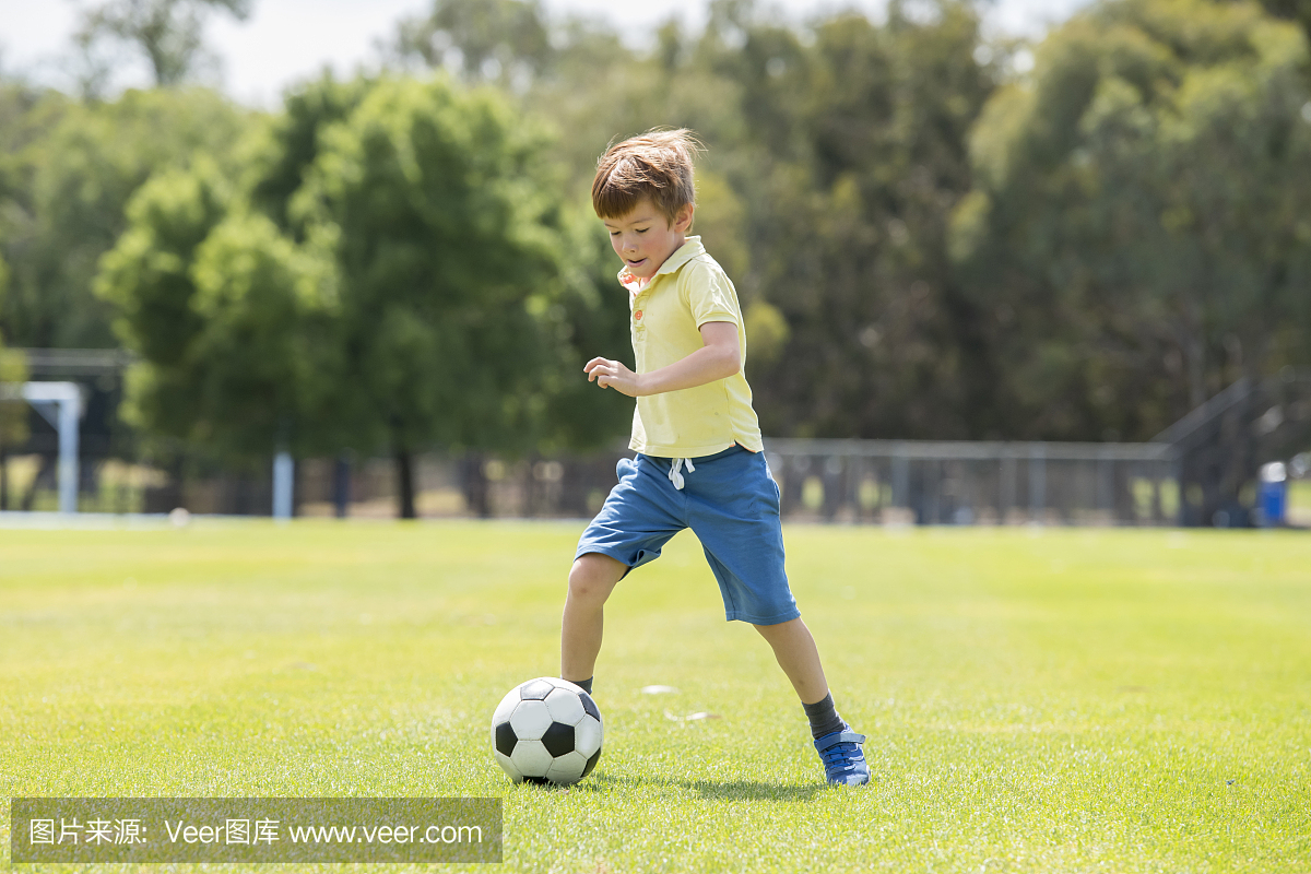 年轻的小孩子7或8岁享受快乐的踢足球足球在