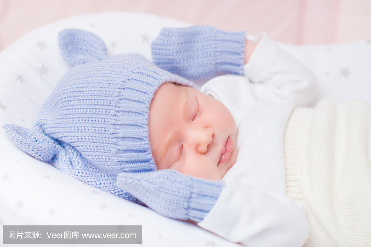 睡着的小宝宝戴耳机和手套的针织帽子