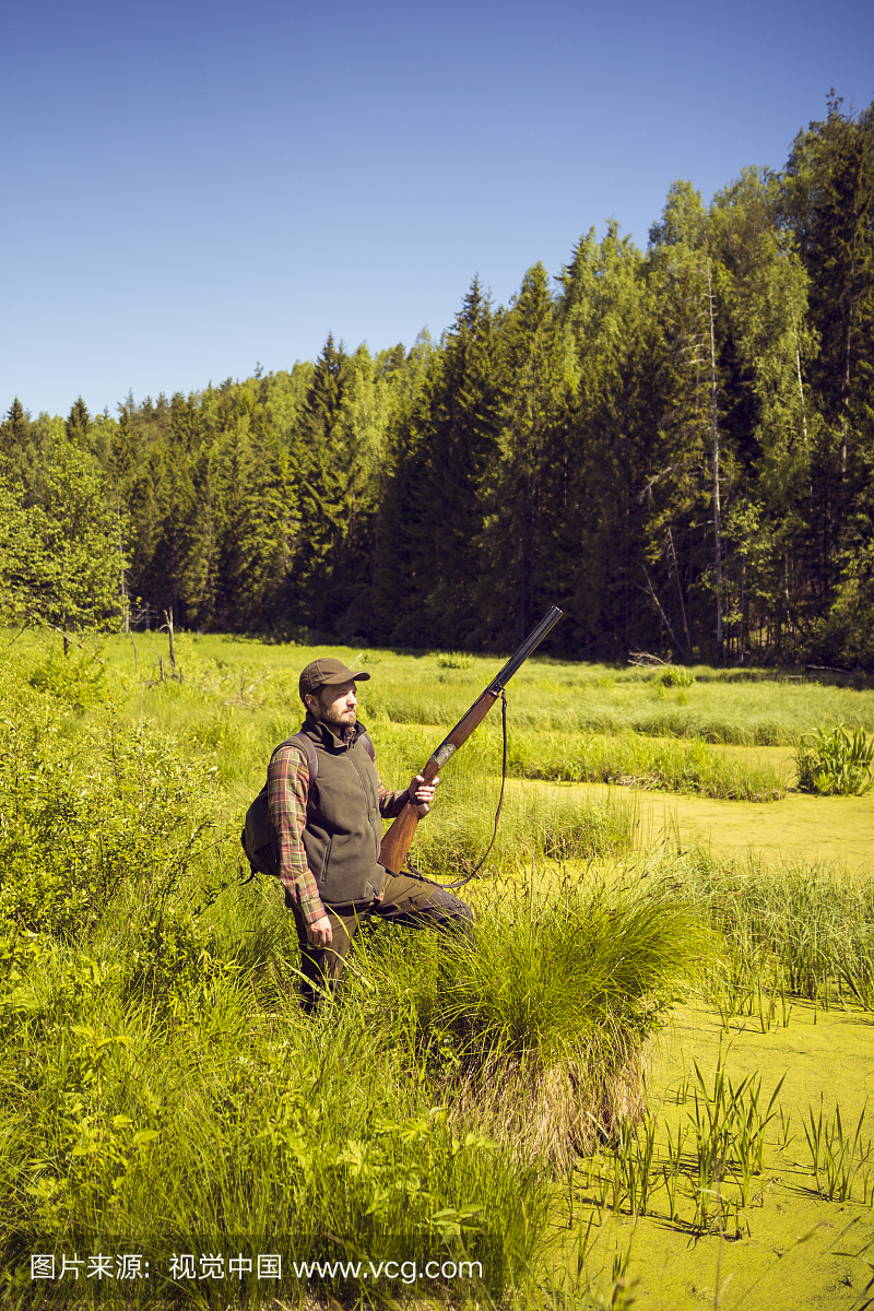 男子与霰弹枪站在一个开放的沼泽风景