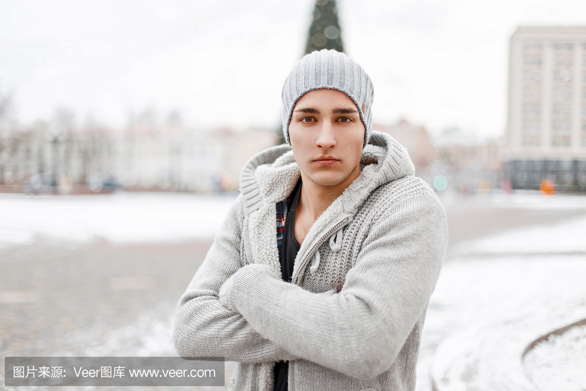 年轻英俊的男人在冬天编织毛衣和帽子是在一个