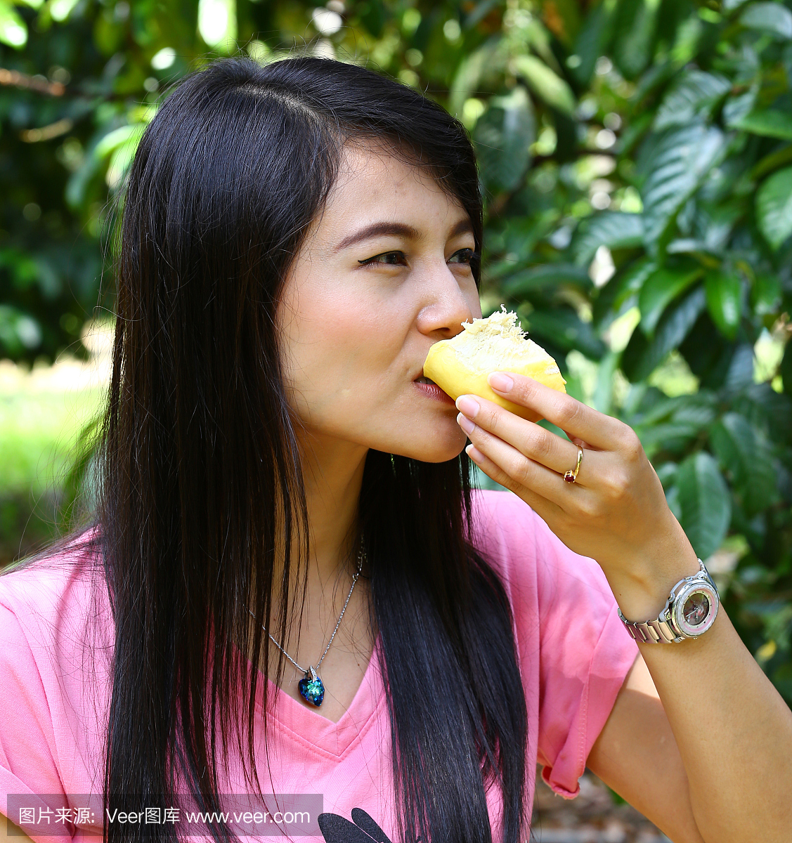 微笑的亚裔女孩在她手中吃榴莲水果