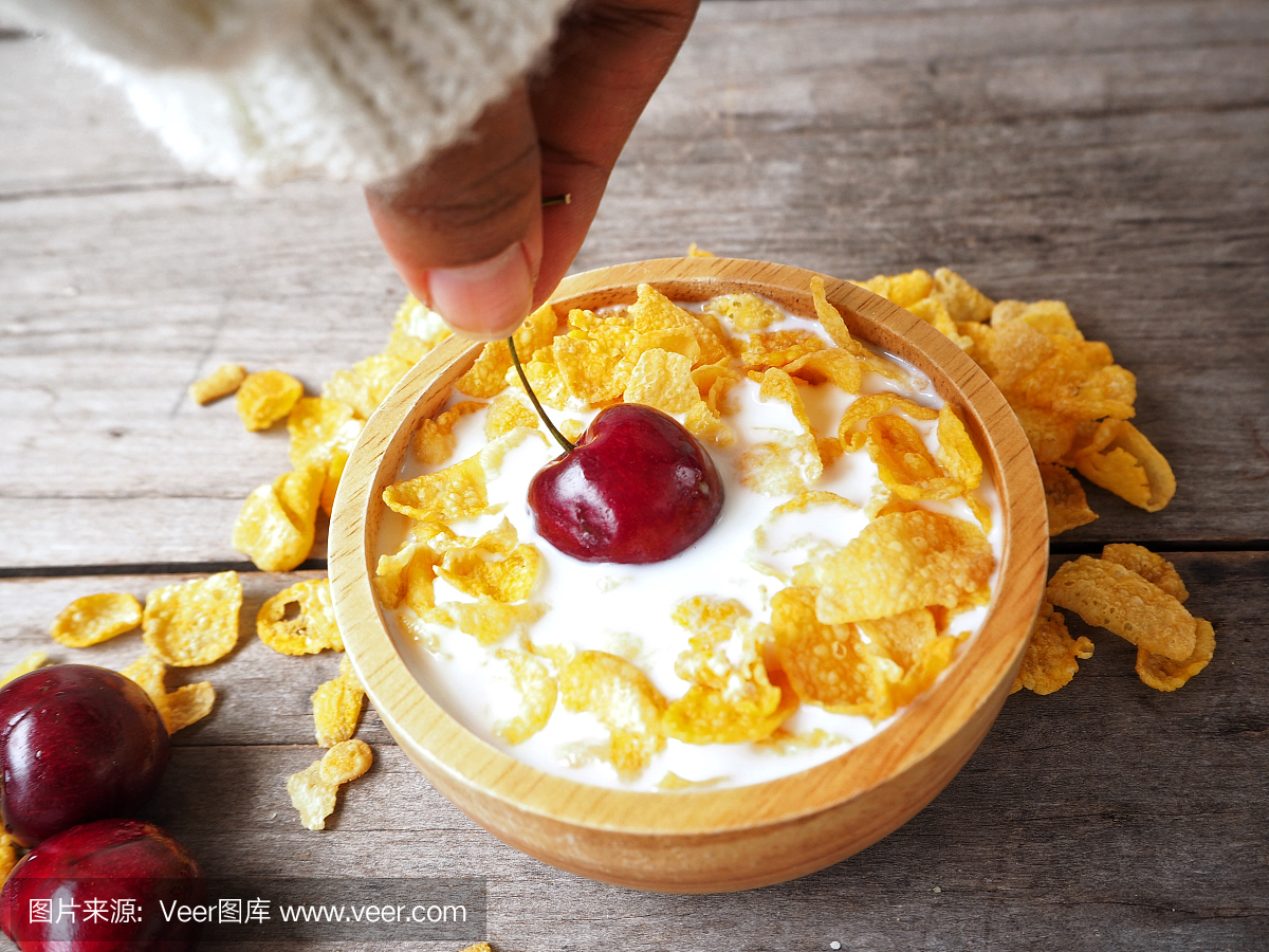 女人吃蛋白玉米片和樱桃与牛奶