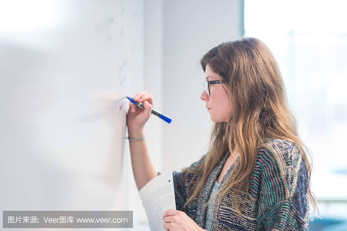 大学生在白板上写出一个数学方程。
