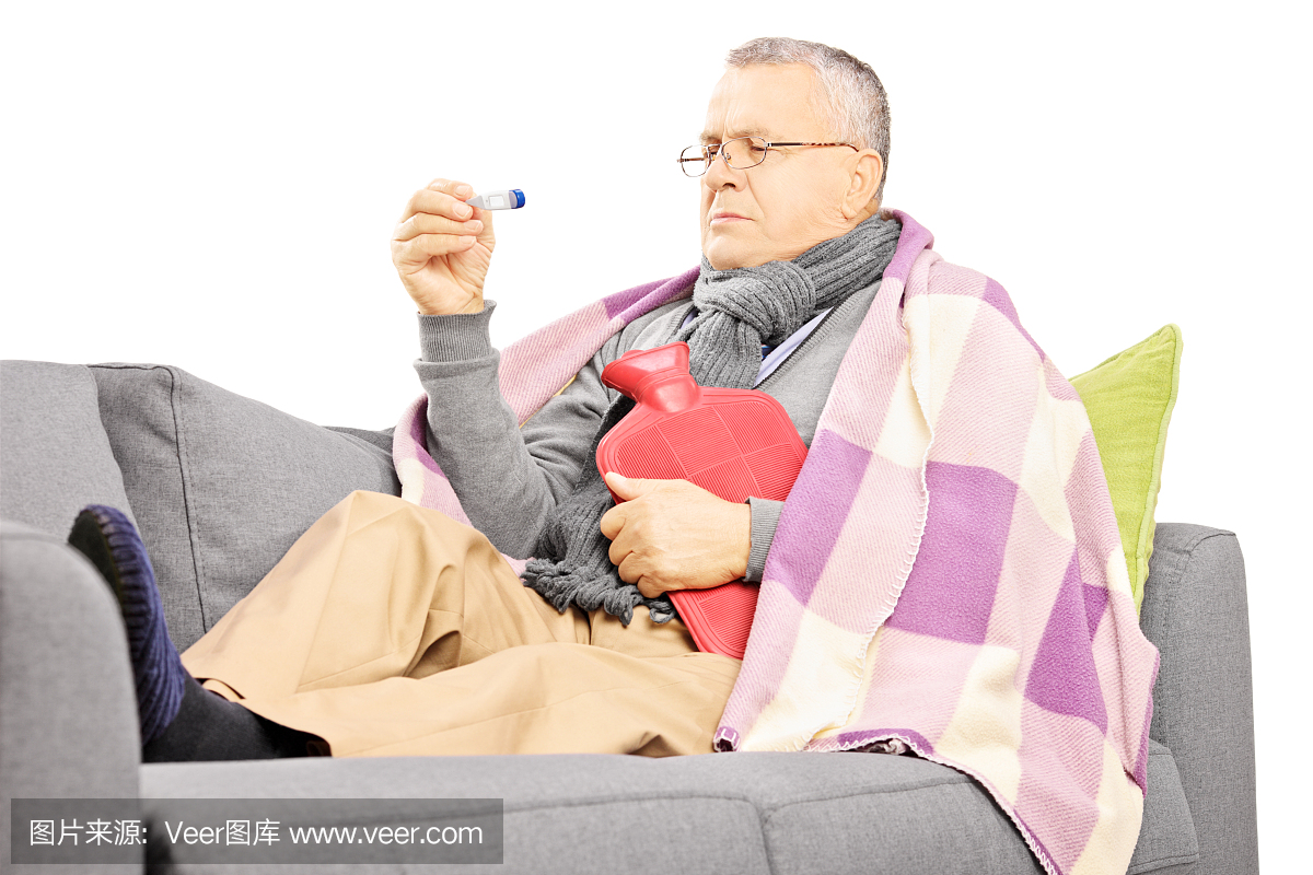 生病的成熟男子在沙发上用热水瓶
